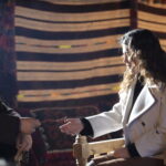 A woman and a man face each other in an interior scene from Halef Episode 17.