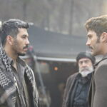 Two men speak outdoors in a scene from Halef Episode 16.