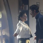 A woman in a white jacket and a man face one another in a room in Halef Episode 22.